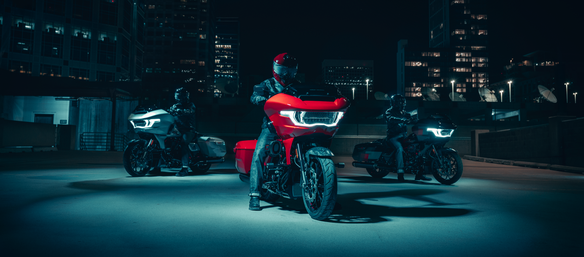 Person on a red Harley-Davidson Road Glide motorcycle in an urban setting at night with illuminated headlights.