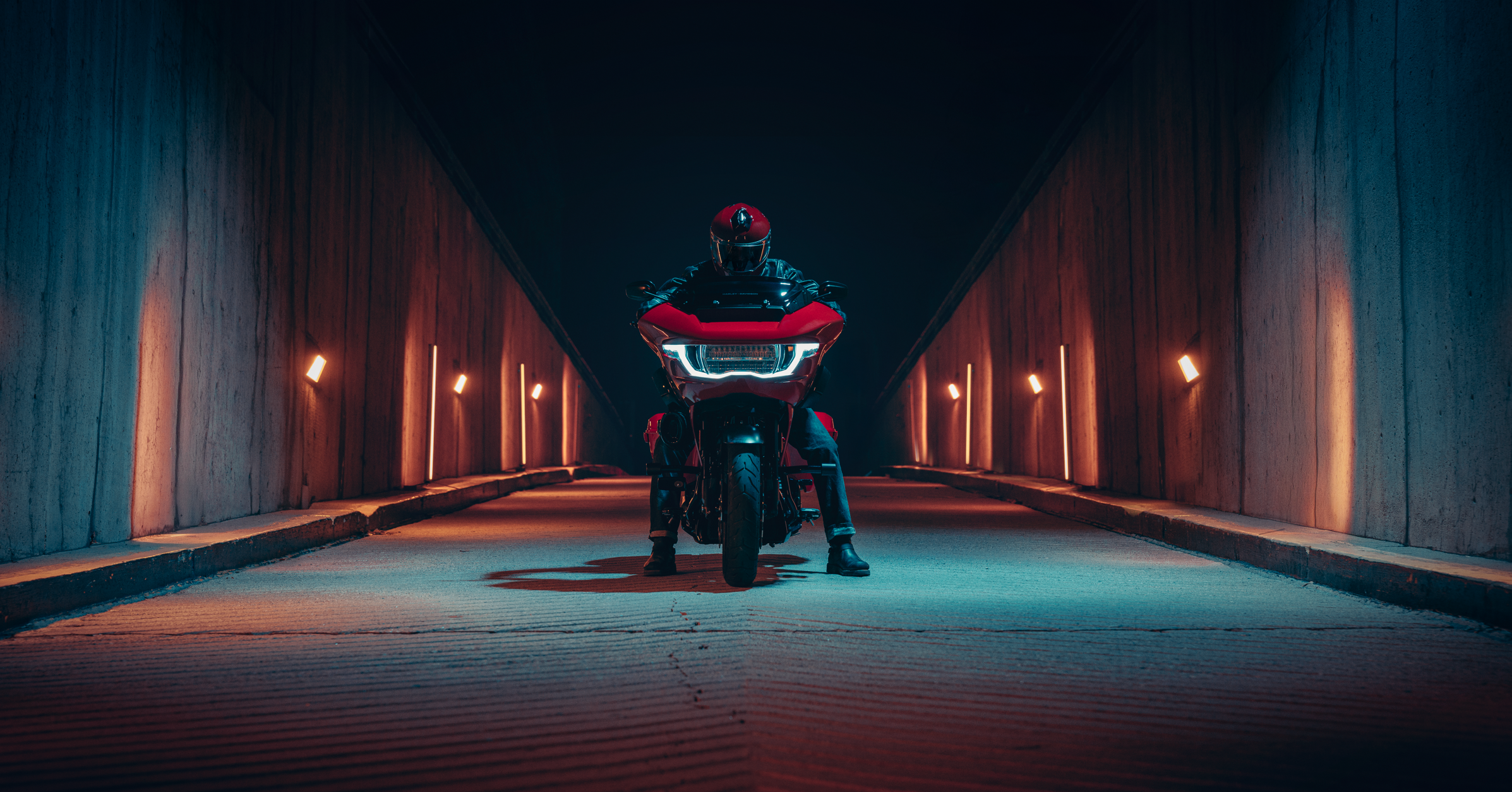 Person on a motorcycle in a dark tunnel with illuminated walls