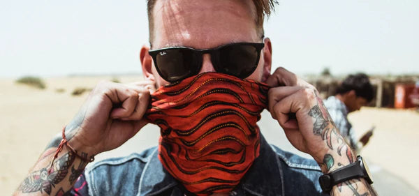 Person wearing sunglasses and a red patterned Headsox bandana in a desert setting