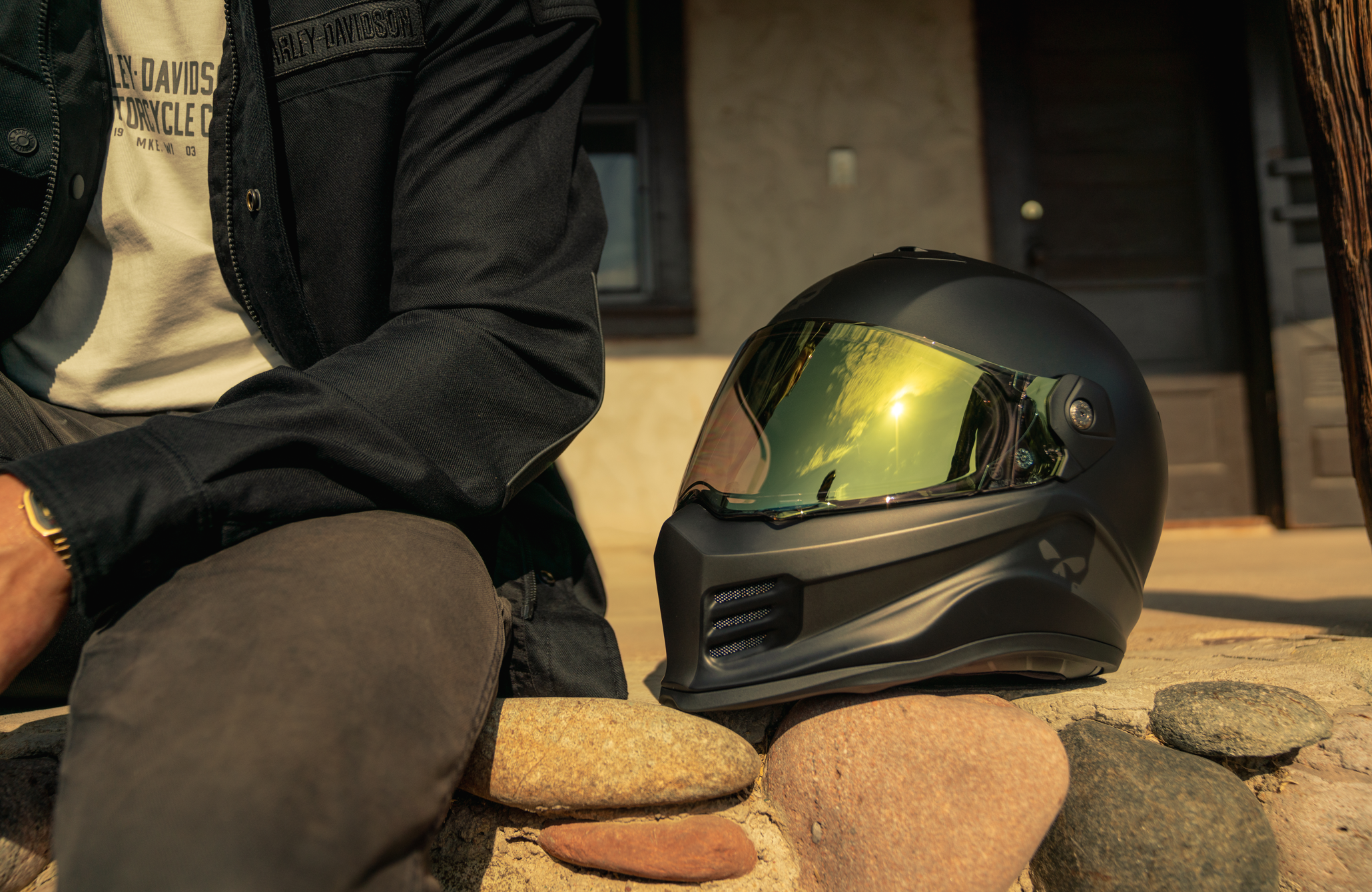 Person sitting on rocks with a black Harley-Davidson helmet nearby