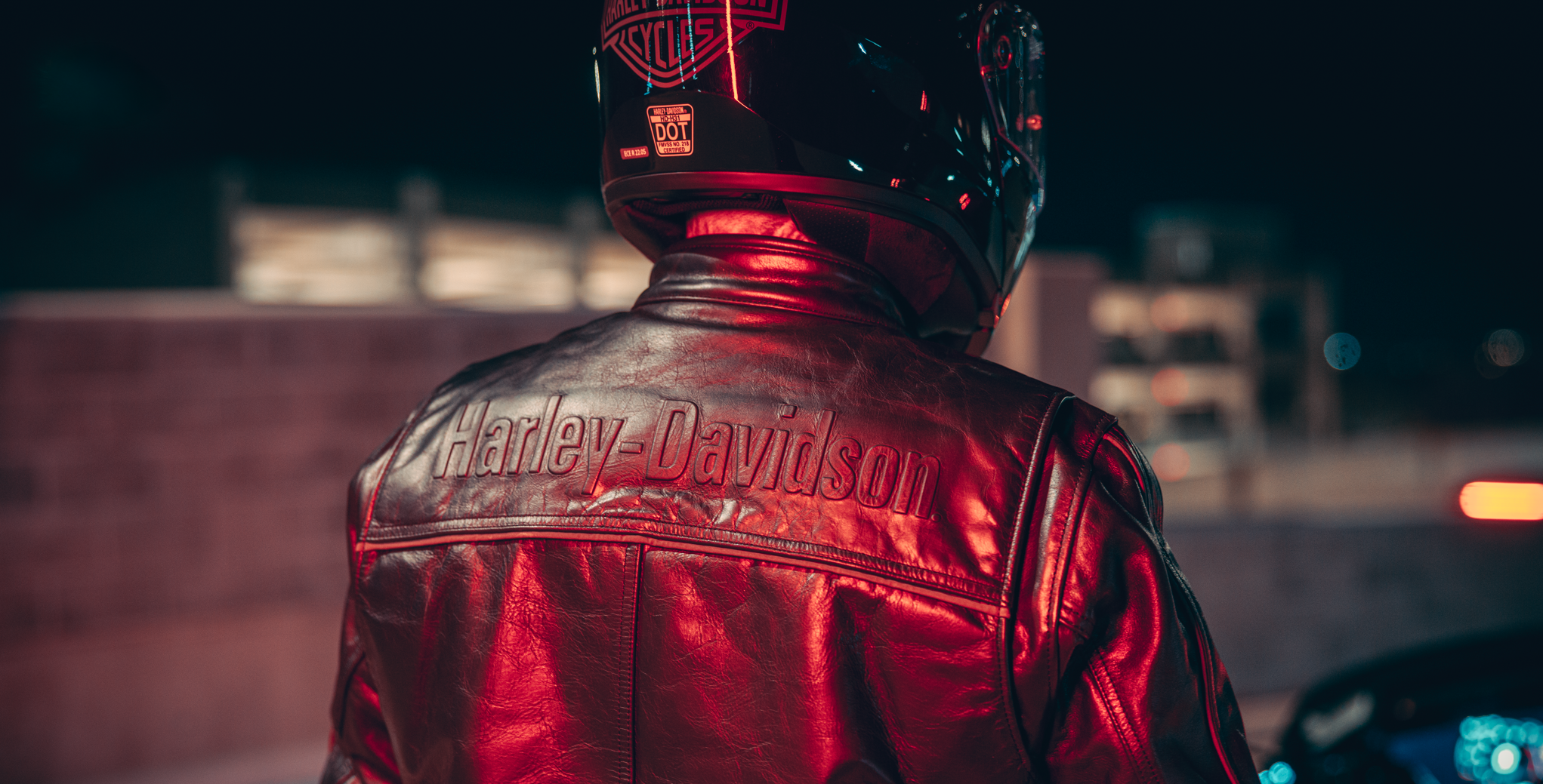 Person wearing a red Harley-Davidson jacket at night.
